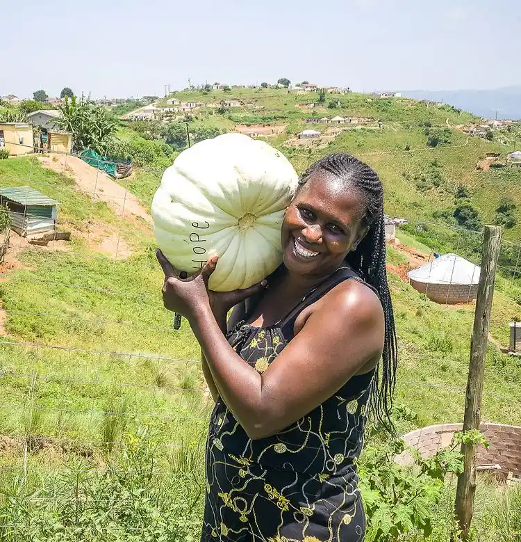 A lady holding an enormous pumpkin (word, Hope, carved into it). Nonto, ECD programme manager, Project Hope. 
