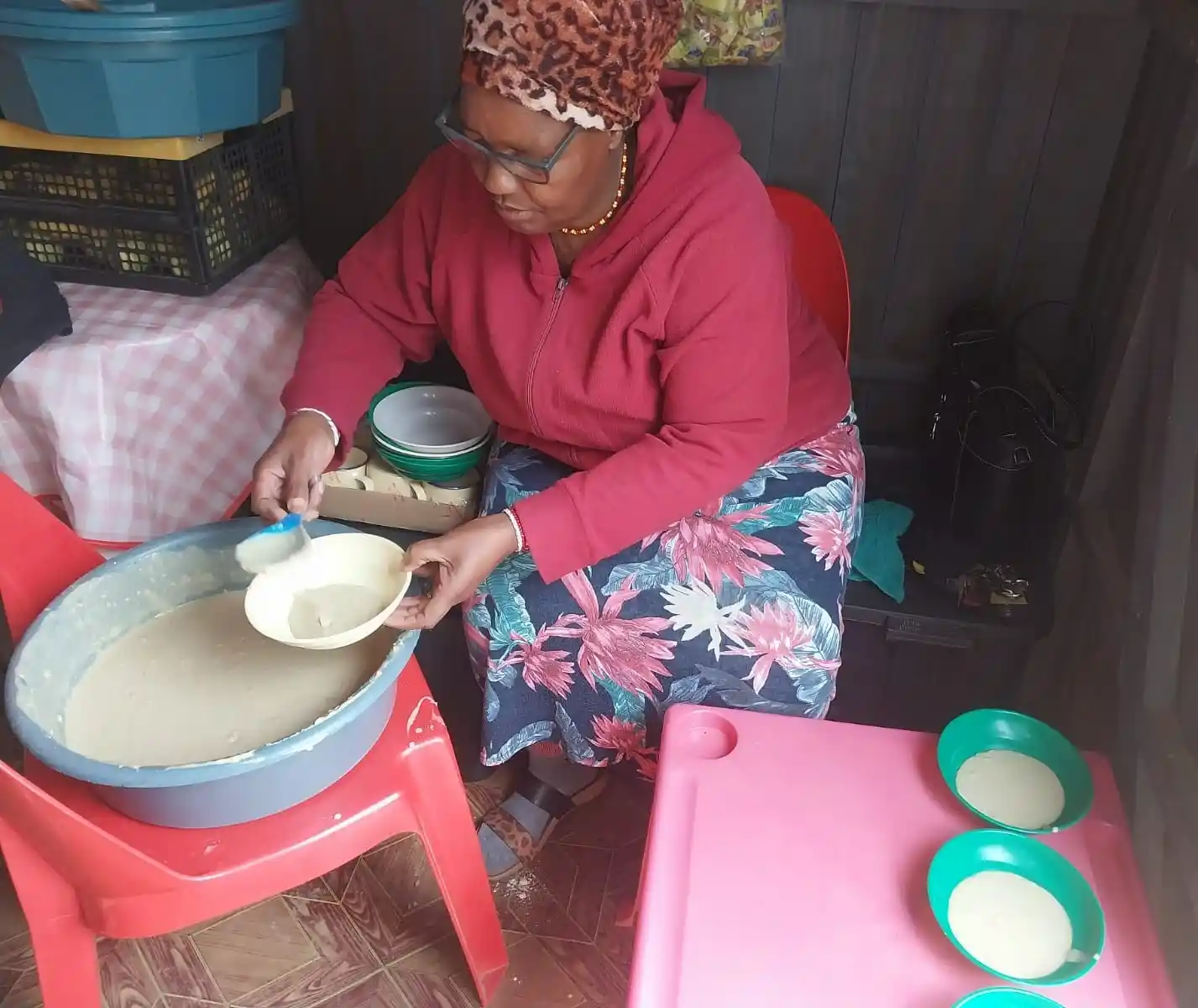 A lady (Gogo) mixing ePap porridge in a large blue bowl and ladling individual portions into small green bowls. ECD Nutrition Project Hope, KZN