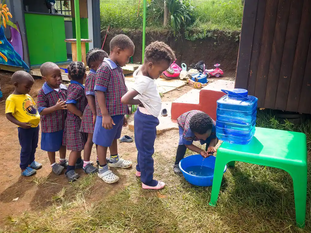 Children lining up to receive clean water. Project Hope ECD Daycare.